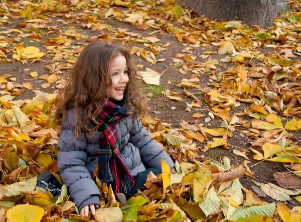 Menina brincando com folhas de outono — Fotografia de Stock