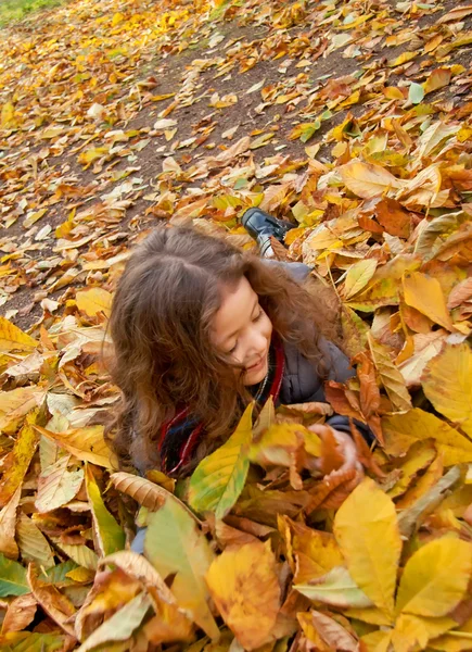 Klein meisje spelen met Herfstbladeren — Stockfoto