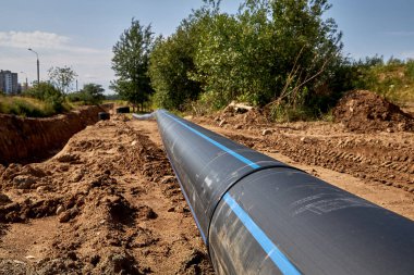 Su borusunun kaynaklı kırbacı yerleştirilmeden önce uzanıyor. İnşaat mühendisliği. Su borusunun kaynaklı kırbacı yerde yatıyor.