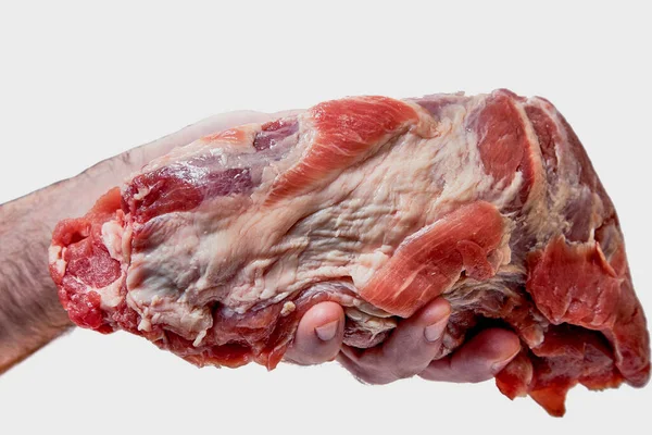 Uma mão segura um grande pedaço de porco cru, isolado em um fundo branco — Fotografia de Stock