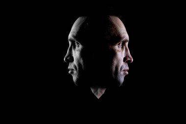 The concept of a portrait of a person from two sides, psychological photography on a dark background.