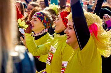 March 8, 2019 Minsk Belarus There's a crowd of happy women in yellow clothes with their hands up at a street concert