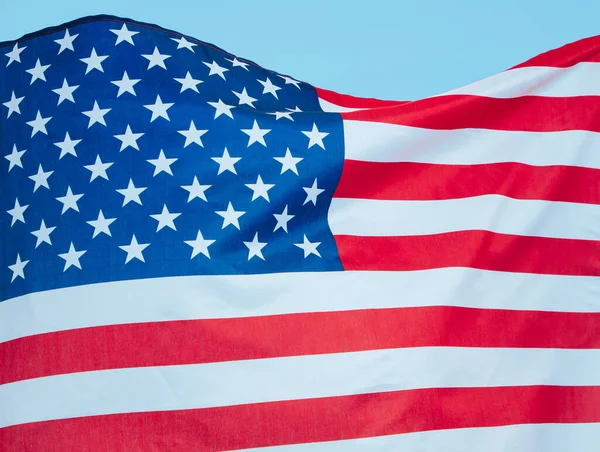 Detailní záběr americké vlajky visící proti jasně modré obloze. — Stock fotografie