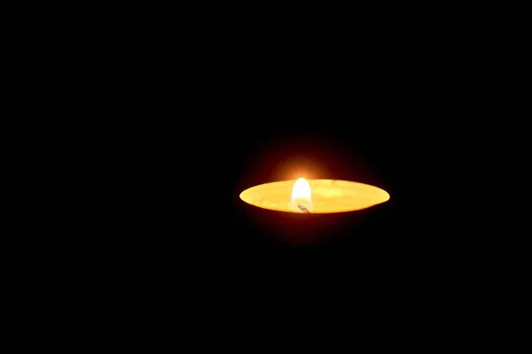 Runde Kerze. schwimmende Kerzen in einem Aluminiumpfahl. Aluminium brennende Teelichter isoliert auf schwarzem Hintergrund. Atmosphäre mit wenig Licht — Stockfoto