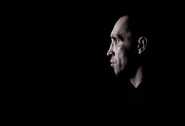 Siyah gömlekli, esmer bir adam.