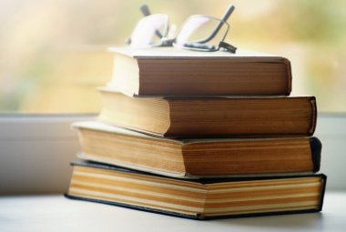 Pencere pervazında kitap, güneş ışığıyla aydınlatılmış..
