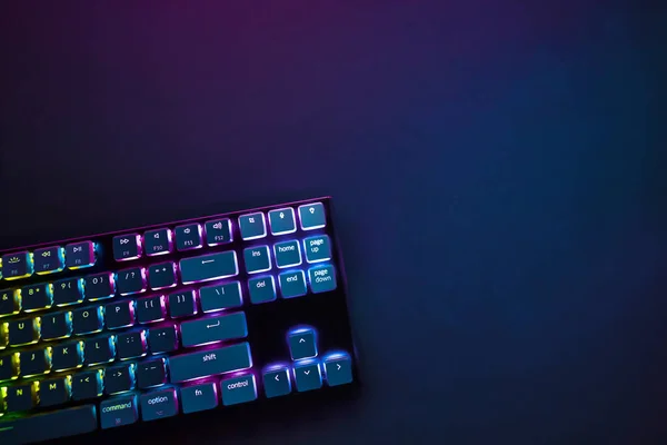 Yukarıdan arka ışıklandırılmış bilgisayar klavyesi görüntüsü. Profesyonel bilgisayar oyunu, esport işi ve online dünya konsepti.