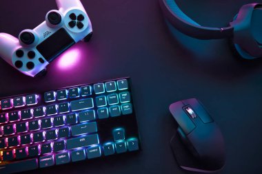 Masada duran çeşitli oyun aksesuarlarının yukarıdan görünüşü. Renkli aydınlatma cihazları. Profesyonel bilgisayar oyunu, esport işi ve online dünya konsepti.