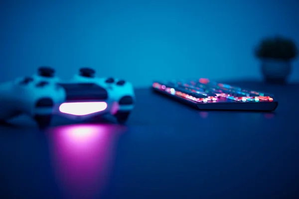 テーブルの上に置くゲームコントローラとキーボードの低角度ビュー 暗いシーンだ プロのコンピュータゲームプレイ スポーツビジネスとオンライン世界の概念 — ストック写真