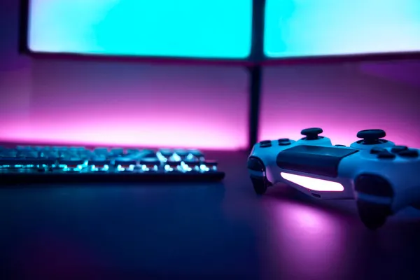 Masada düşük açılı oyun denetleyici var. Arka planda çift ekran ve pembe ışıklı duvar. Profesyonel bilgisayar oyunu, esport işi ve online dünya konsepti.