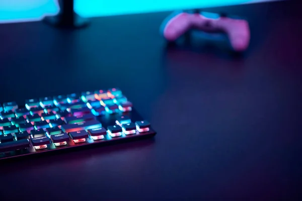 暗いテーブルの上にカラーバックライトとゲームコントローラーでキーボードをゲーム プロのコンピュータゲームプレイ スポーツビジネスとオンライン世界の概念 — ストック写真