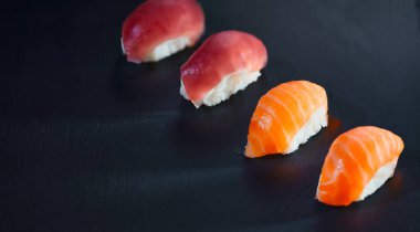 Siyah arkaplana karşı hazırlanmış dört suşi parçasının yüksek açılı görüntüsü. Japon yemeği ve sağlıklı yeme konsepti.