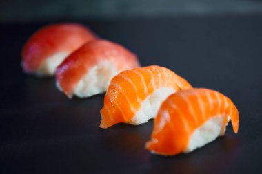 Siyah arka plana karşı dört suşi parçası hazırladım. Japon yemeği ve sağlıklı yemek konsepti taş masada..