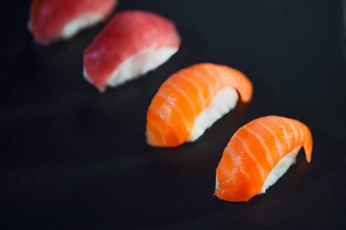 Siyah arka plana karşı dört suşi parçası hazırladım. Japon yemeği ve sağlıklı yemek konsepti taş masada..