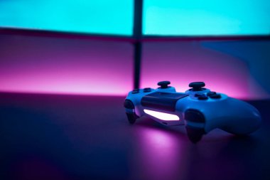 Masada düşük açılı oyun denetleyici var. Boş çift ekran ve arka planda pembe duvar. Profesyonel bilgisayar oyunu, esport işi ve online dünya konsepti.