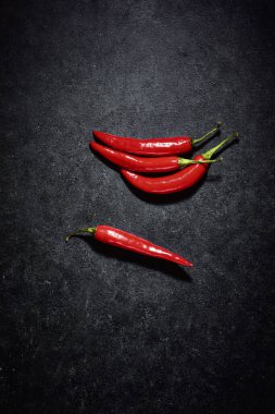 Kırmızı biberler koyu arkaplanda. Işıltılı sebze yansıtan ışığın yukarıdan aşağı görüntüsü. Mutfakta baharatlı malzemeler var..