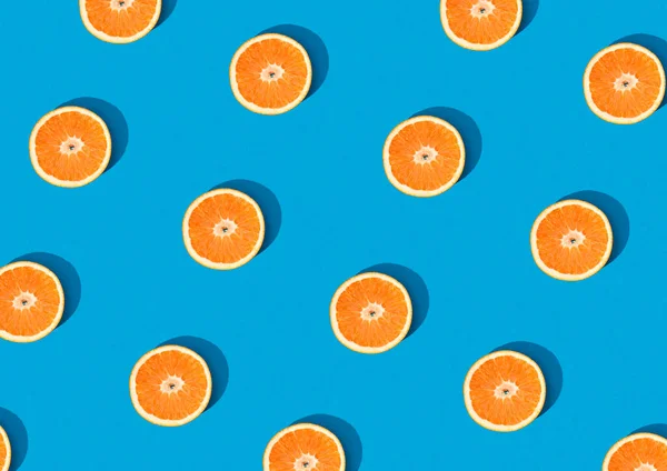 Top view orange fruit half cut pattern on sky blue background isolated. Fun creative fruit trendy abstract wallpaper design. Citrus fruit pattern creative trendy layout wallpaper