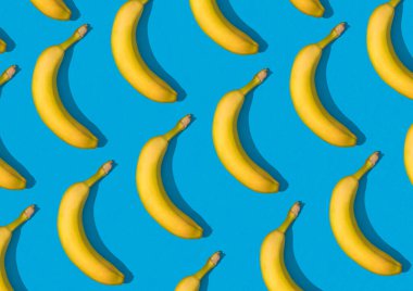 Colorful pattern of yellow bananas on sky blue background isolated. Wallpaper of fruit pattern top view