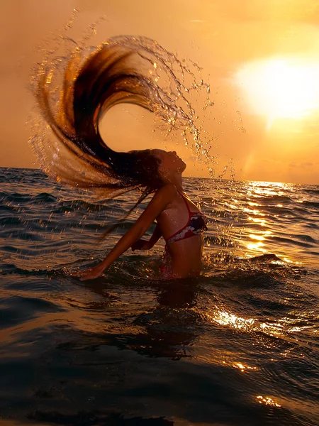 Fille dans la mer au coucher du soleil avec éclaboussure — Photo