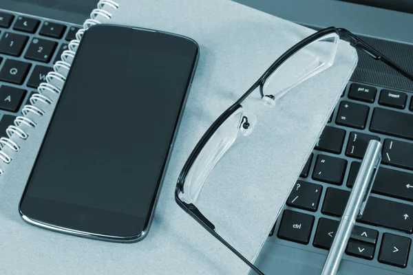 Мобильный телефон и очки на ноутбуке — стоковое фото