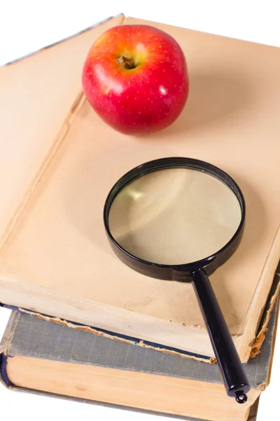 Age-old books, apple and magnifying glass — Stock Photo, Image
