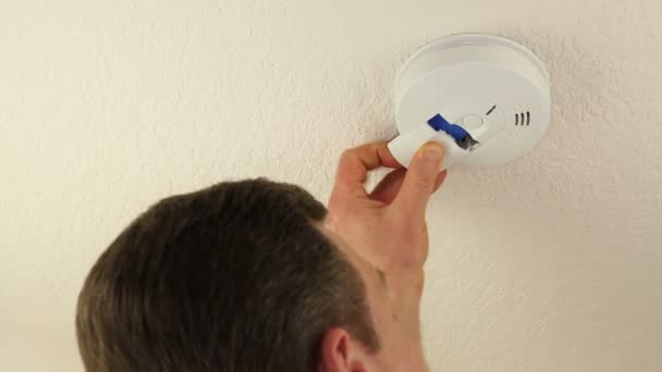 Homme changeant la batterie du détecteur de fumée de plafond — Video