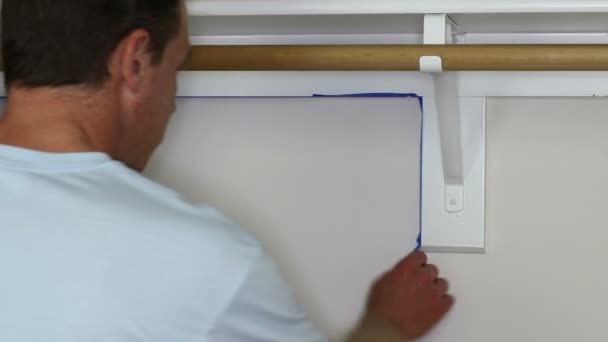 Man Removing Blue Painters Tape After Painting a Small Foyer Closet — Stock Video