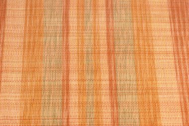 Colorful multi-colored abstract textile place mat with rows of color variation. Multiple warm and inspirational colors of orange, green and red in rows of this weaved textile place mat close-up