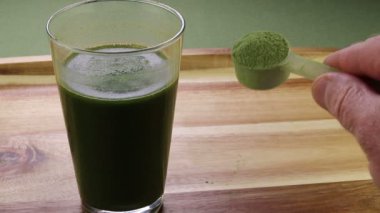 Organik kereviz tozu ve organik aloe vera suyu bir erkek elinin yanında bir kepçe dolusu kereviz tozu gösteriyor. Erkek el, aloe vera suyu ve kereviz tozu ile bir kepçe kereviz tozu gösteriyor..