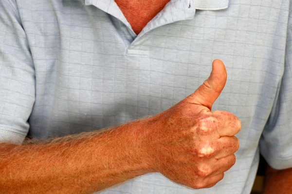 One right hand of an adult male caucasian expressing goodness with his thumb raised up. Close-up of adult caucasian males raised thumb of his right hand gesturing approval with thumbs up gesture