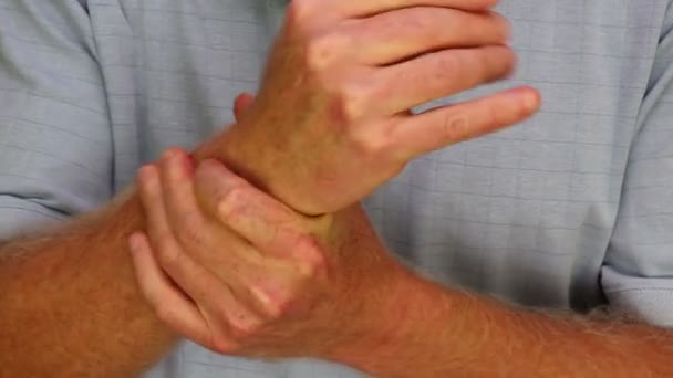 마사지 오른쪽 손목에 클로즈업 셔츠를 코카서스 남성의 왼손은 통증을 완화하기 — 비디오