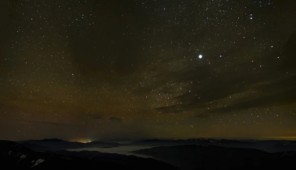 Molnigt stjärnhimmel över dimmiga bergen — Stockfoto