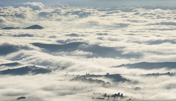 Sabah bulutlar dağlar, ormanlar ve köyleri üzerinden — Stok fotoğraf