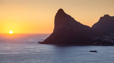 Güney Afrika 'daki Cape Town yakınlarındaki Hout Bay' den gün batımında ayrılan bir balıkçı teknesi. Chapman Tepesi 'nden görüldüğü gibi..