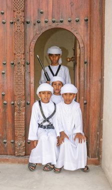 SHARJAH, UAE - APRIL 14, 2005: Four brothers in national dress, outside a restored house in the Sharjah Heritage Area, on their way to Sharjah's Heritage Days Festival.