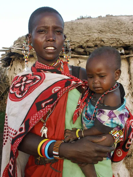 KENIA, MASAI MARA - 6 DE ENERO: Madre sosteniendo a su bebé y de pie —  Fotos de Stock