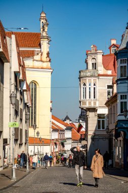 Vilnius, Litvanya - 10 Ekim 2021: Pilies Caddesi 'nde yürüyen turistler, Vilnius Eski Kasabası' nın en eski ve en gösterişli caddesi. St. John 's kilisesi solda görünüyor..