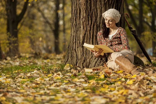 Молодая женщина, читающая в осеннем лесу — стоковое фото