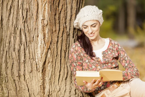 Giovane donna che legge nella foresta autunnale — Foto Stock