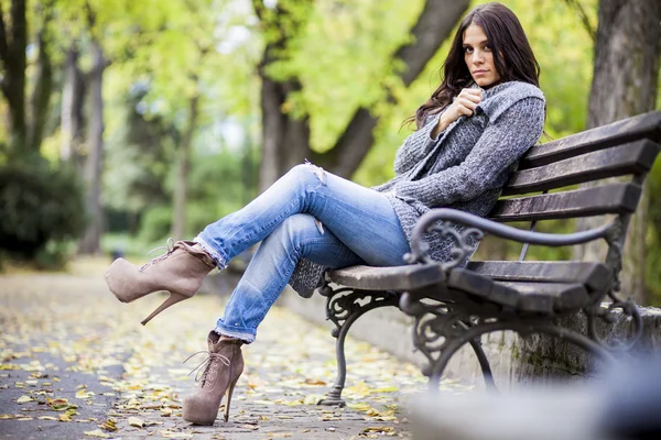 Jovem mulher no banco no parque — Fotografia de Stock