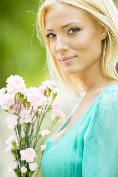 若いブロンドの女性の花を持つ — ストック写真