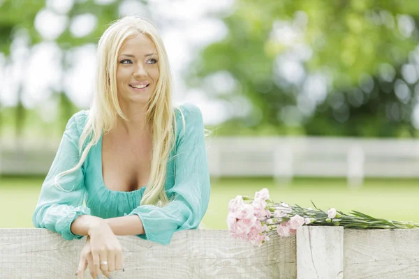 Jonge blonde vrouw door het hek — Stockfoto