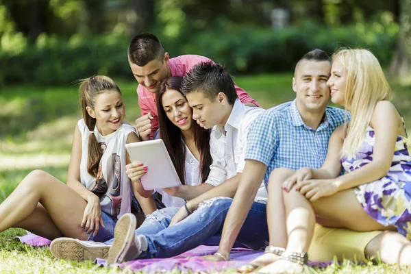 Teenagers in the park with tablet — Stock Photo, Image