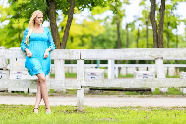 Young blond woman by the fence — Stock Photo, Image