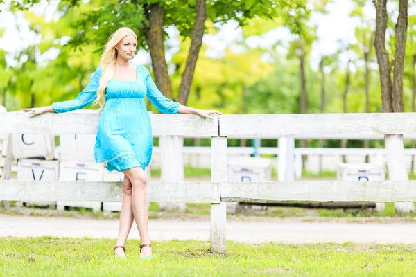 Young blond woman by the fence — Stock Photo, Image