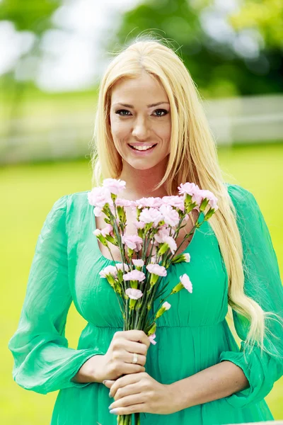 若いブロンドの女性の花を持つ — ストック写真