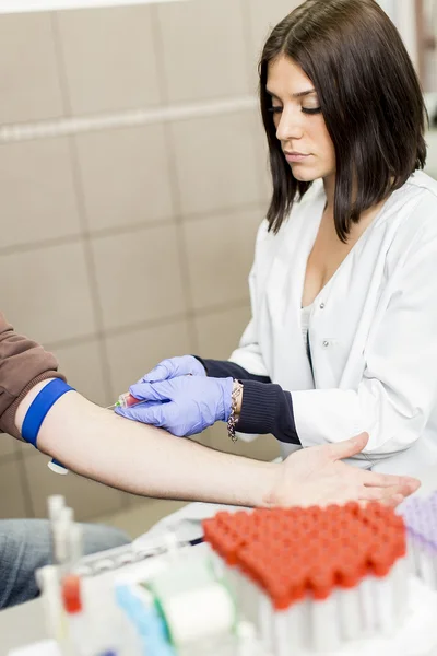 Jovem mulher fazendo amostragem de sangue em laboratório médico moderno — Fotografia de Stock