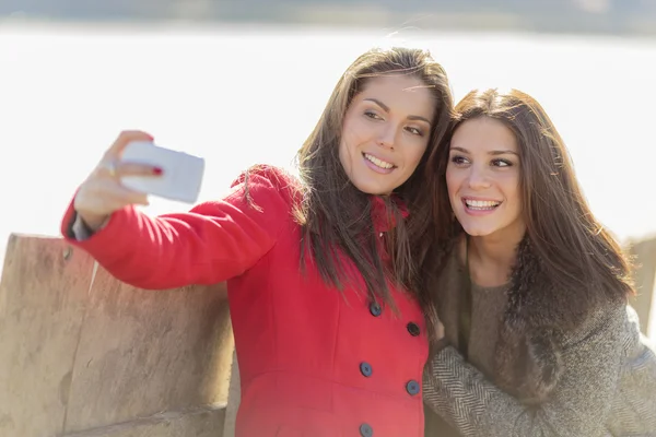 Šťastné mladé ženy s fotografií s mobilním telefonem — Stock fotografie