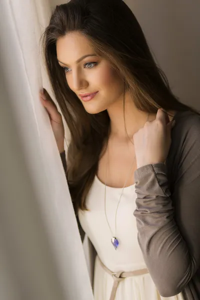 Kaunis nuori nainen ikkunan vieressä — kuvapankkivalokuva