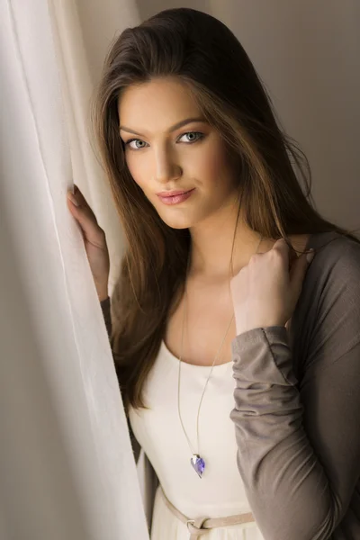 Mujer joven y bonita junto a la ventana — Foto de Stock